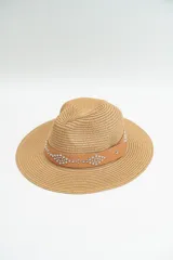 Sombrero de paja color beige con cinta de cuero sintético color tostado decorada con tachas metálicas plateadas.