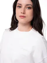 Buzo de corte relajado color blanco, con cuello redondo, mangas largas y puños acanalados. Presenta un pequeño parche con el logo de la marca en el puño izquierdo.