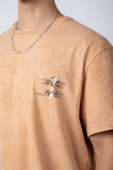 Remera de corte semi-oversize en color naranja con efecto de lavado tipo snow. Presenta un pequeño estampado gráfico en el pecho y cuello redondo.