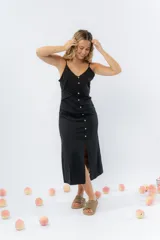 Vestido midi celeste de tejido tipo seda fría, con breteles finos regulables, botones de madera decorativos en el frente, pliegues decorativos en la cintura y cierre invisible en el costado.