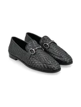 Mocasín de cuero negro entrelazado con aplique metálico plateado.