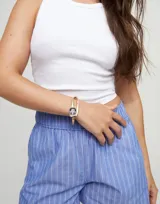 Pulsera rígida dorada con cristal facetado negro en el centro.