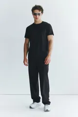 Pantalón deportivo negro de corte estándar y piernas rectas, confeccionado en tejido funcional ripstop con tecnología DryMove™. Cuenta con cintura elástica con cordón de ajuste oculto, bolsillos laterales con cierre y detalles perforados en las piernas.