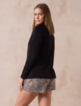 Pijama de dos piezas compuesto por una remera negra de manga larga con escote redondo y bolsillo en el pecho, y un short con estampado animal print.