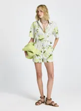 Short de tela con estampado floral en tonos blanco, verde y amarillo. Cintura elástica con cordón ajustable y puntas metálicas, bolsillos laterales y traseros.
