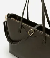 Cartera tipo shopper de gran tamaño, confeccionada en cuero sintético (PU) color verde oscuro. Presenta un diseño de trapecio invertido con asas de mano fijas, correa larga ajustable y desmontable, cierre superior con cremallera y detalles metálicos dorados.