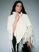 Poncho de lana merino color blanco, con diseño de trenzas, cuello alto tipo polera y terminación con flecos largos en el ruedo.