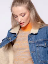 Campera de jean blanca con interior de corderito color beige, dos bolsillos grandes en la parte frontal y siete botones metálicos.