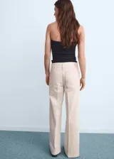 Pantalón de jean estilo wide leg color beige, con tiro alto, cierre frontal de cremallera y botón, y dos bolsillos de parche en la parte delantera.