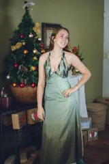 Vestido largo con estampado tie-dye en tonos violeta y fucsia, escote en V con detalles bordados dorados, cut-outs laterales bajo el busto y tirantes finos que se cruzan y atan en la espalda.