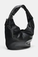 Bolso de hombro tipo saca en formato maxi, confeccionado en material sintético con acabado liso. Cuenta con asa única para llevar al hombro, cierre imantado en el compartimento principal, bolsillo lateral con cremallera y bolsillo interior con cierre.