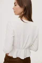Blusa manga larga de color negro con escote en V profundo y lazo ajustable en el frente, confeccionada en tejido liviano con corte evasé.