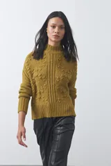 Polera de tejido de punto color marrón, con cuello alto y diseño de textura con relieves y trenzas. Posee mangas largas con puños acanalados.