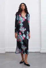 Vestido midi negro con estampado floral en tonos celeste, rosa y verde. Posee escote en V y tajos laterales.