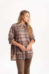 Camisa de corte oversize con estampado de cuadros en tonos marrones y beige. Presenta cuello clásico, cierre frontal con botones y mangas largas con puños simples.