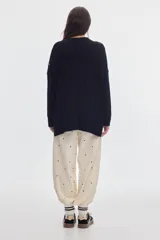 Buzo negro de tejido de ochos, con cuello redondo y diseño oversized de corte largo y amplio con tajos laterales.