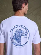 Remera blanca de algodón con estampa circular en la espalda que presenta la ilustración de un perro y el texto Benson & Thomas 1968 Modern Classics en color azul.