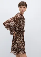 Vestido corto de tejido fluido con estampado animal print de leopardo. Presenta cuello redondo con cierre de lazo, mangas largas con puños elásticos y volados, y diseño evasé con falda de capas.