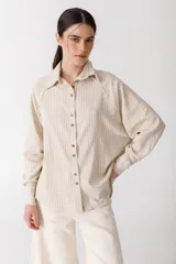 Camisa de manga larga color beige con rayas verticales finas, cuello clásico y cierre frontal con botones.