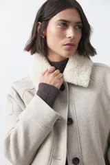 Campera corta de paño color gris con cuello de corderito blanco, cierre frontal con botones y bolsillos laterales.