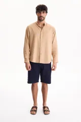 Camisa de manga larga color beige con cuello mao y cierre frontal con botones.