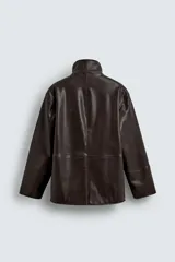 Cazadora de corte relajado confeccionada en tejido efecto piel color marrón oscuro. Presenta cuello subido con interior forrado en tejido de cuadros, manga larga, bolsillos de vivo en la cadera y cierre frontal con cremallera oculta por solapa con botones a presión.