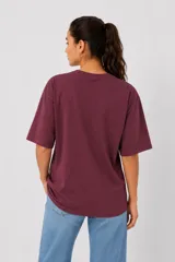 Remera de algodón color bordó, de corte holgado y manga corta, con cuello a la base y estampa frontal con la palabra 'WILD' en animal print.