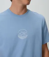 Remera de algodón celeste de corte comfort y holgado, con cuello redondo, manga corta y pequeño estampado circular en el frente.