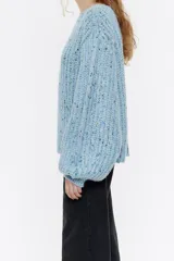 Jersey negro de punto con hilos de colores entretejidos, corte recto, escote barco y mangas largas abullonadas.