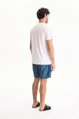 Remera blanca de algodón, de corte regular y manga corta, con estampa frontal centrada con texto en tonos oscuros.