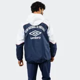 Campera de lluvia Umbro del Club Nacional de Football, con diseño de bloques de color blanco y azul marino. Presenta capucha, cierre frontal completo, puños elásticos y detalles de piping en color rojo. Incluye logo de la marca y escudo del club en el pecho.