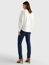 Blusa blanca de algodón orgánico con cuello en V, mangas largas abullonadas con puños abotonados y detalles de encaje vertical.