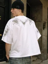 Remera de algodón pesado con corte boxy fit, color blanco con efecto acid wash. Presenta un estampado frontal y en mangas que simula una armadura medieval con acabado gastado.