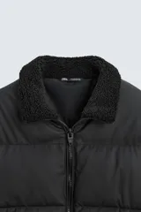 Cazadora acolchada de hombre con acabado engomado, cuello subido con interior de borreguillo, cierre frontal de cremallera, bolsillos laterales con cremallera y puños y bajo elásticos.