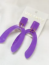 Aros colgantes de acrílico color lila, con forma geométrica rectangular en la parte superior y forma de U en la parte inferior.