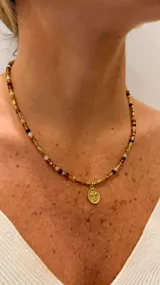 Collar de cuentas de cristal checo en tonos marrones y hematita dorada, con dije central de acero en forma de cruz mini.