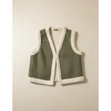 Chaleco estilo gamulán en color verde militar, con forro interior y bordes de corderito sintético en tono crema. Presenta un diseño sin mangas, ideal para usar sobre prendas de abrigo.