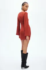 Vestido corto de punto texturizado en color terracota, con escote bote, mangas largas amplias y detalle de tiras anchas para anudar en la cadera.