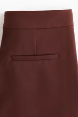 Pantalón acampanado de color bordó, de talle alto con pretina prolongada y cierre oculto. Presenta bolsillos al bies en los laterales, bolsillos decorativos en la parte trasera y perneras amplias con pliegues marcados tanto en el frente como en la espalda.