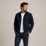 Chaqueta de gabardina azul marino con cierre frontal, cuello clásico y diseño minimalista de corte recto.