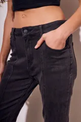 Pantalón de jean negro con corte flare, tiro medio y ruedo desflecado.