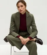 Pantalón de sastrería modelo wide leg color verde militar, confeccionado en crepé. Presenta pliegues delanteros, cintura con trabillas e incluye un cinturón de gamuza a tono.