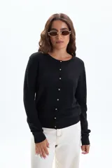 Saco de punto básico color negro, con cuello redondo y cierre frontal de botones dorados.