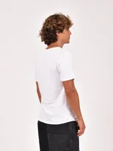 Remera blanca de manga corta con cuello redondo y un bolsillo simple en el pecho.