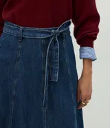 Pollera midi de corte evasé confeccionada en denim azul oscuro. Presenta recortes verticales, cintura alta con trabillas y cinturón desmontable del mismo tejido. Cuenta con cierre trasero oculto.