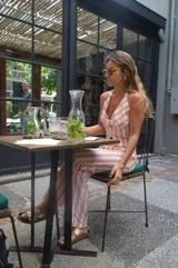 Mono largo a rayas verticales color naranja y blanco, con escote halter y corte ajustado.