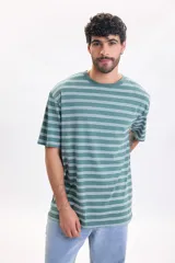 Remera manga corta de corte oversize en color verde con diseño de rayas horizontales blancas y efecto lavado.