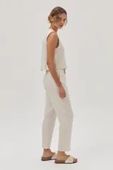 Conjunto color beige compuesto por un top sin mangas y un pantalón chino de lino metalizado, con tiro medio-alto, pierna recta, bolsillos laterales y traseros.