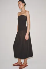 Vestido midi de corte bandeau con escote palabra de honor y detalle de vuelta en el pecho. Presenta una cintura entallada con pliegues y una falda con volumen en tejido combinado a tono.
