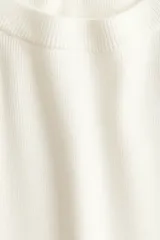 Remera de punto tupido color blanco crudo, con cuello redondo acanalado, mangas cortas con hombros caídos y bajo recto.